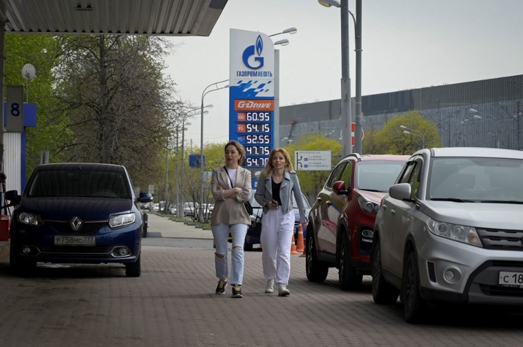 Dua wanita ini berjalan melewati pompa bensin milik produsen minyak Rusia, Gazprom Neft, di Moskwa, Rusia, 11 Mei 2022. 