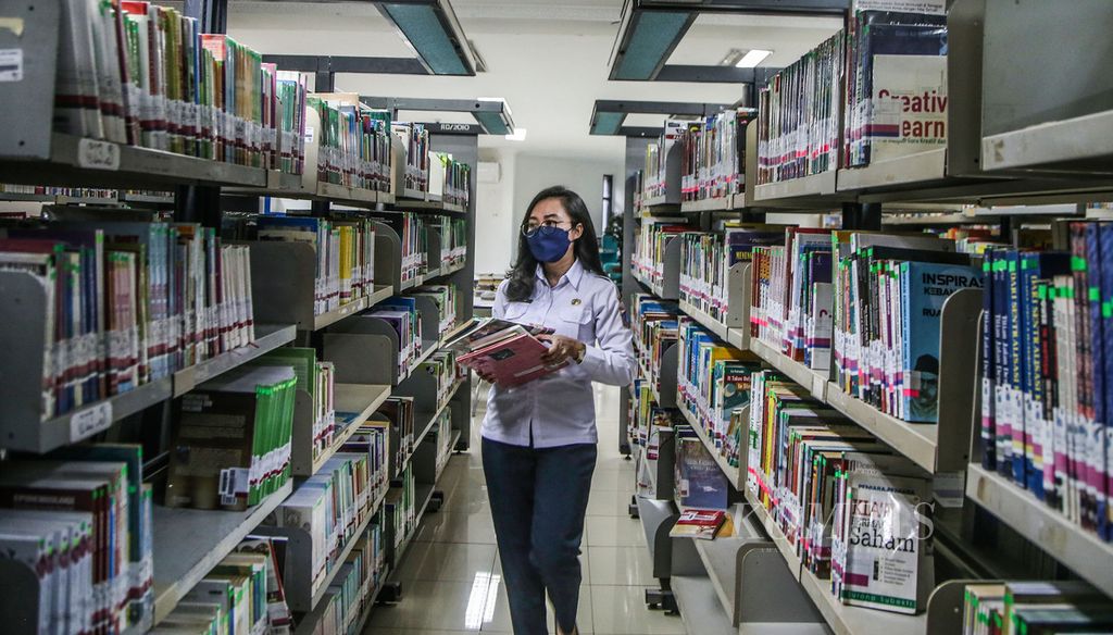 Pustakawan melakukan penataan bahan pustaka <i>(shelving)</i> di Perpustakaan Umum Daerah Jakarta Selatan, Gandaria, Jakarta (27/10/2021). 