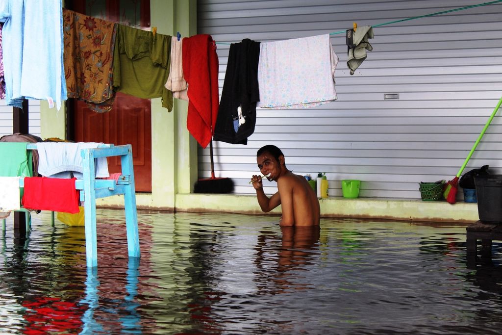 Warga Jalan Arut, Kelurahan Palangka, Kota Palangkaraya, mandi dan menyikat gigi di tengah banjir yang melanda, Kamis (18/11/2021). Di Palangkaraya, 20 kelurahan terendam banjir di lima kecamatan.