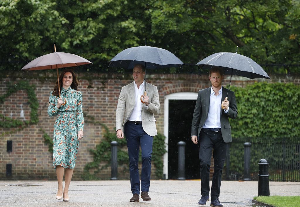 Pangeran William (tengah) berjalan bersama dengan istrinya, Kate - Duchess of Cambridge - dan Pangeran Harry di taman Puri Kensington, London pada 30 Agustus 2017. 
