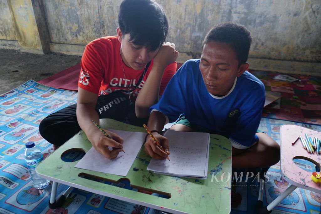 Seorang sukarelawan membimbing Udin (23, kanan), seorang pemuda tunawicara, belajar menulis dalam kelas informal mingguan yang diselenggarakan Komunitas Dinding Manado di lantai 3 gedung utama Pasar Bersehati Manado, Sulawesi Utara, Sabtu (11/11/2023). 