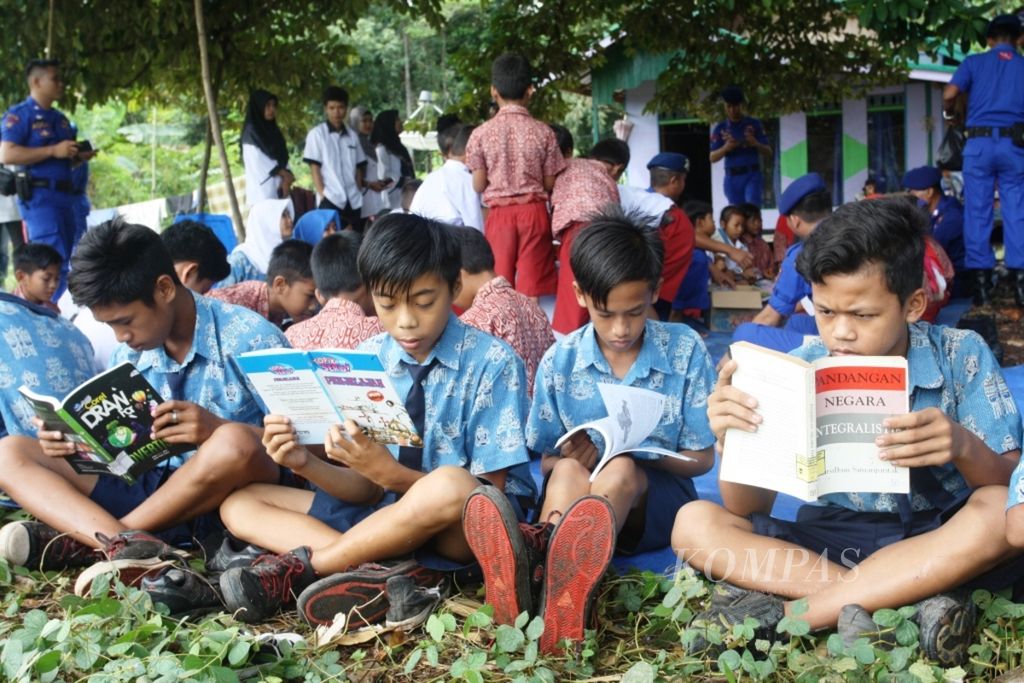 Anak-anak di Kalimantan Tengah asyik membaca buku, Jumat (21/4/2017), yang didistribusikan oleh Polisi Air Polda Kalteng.