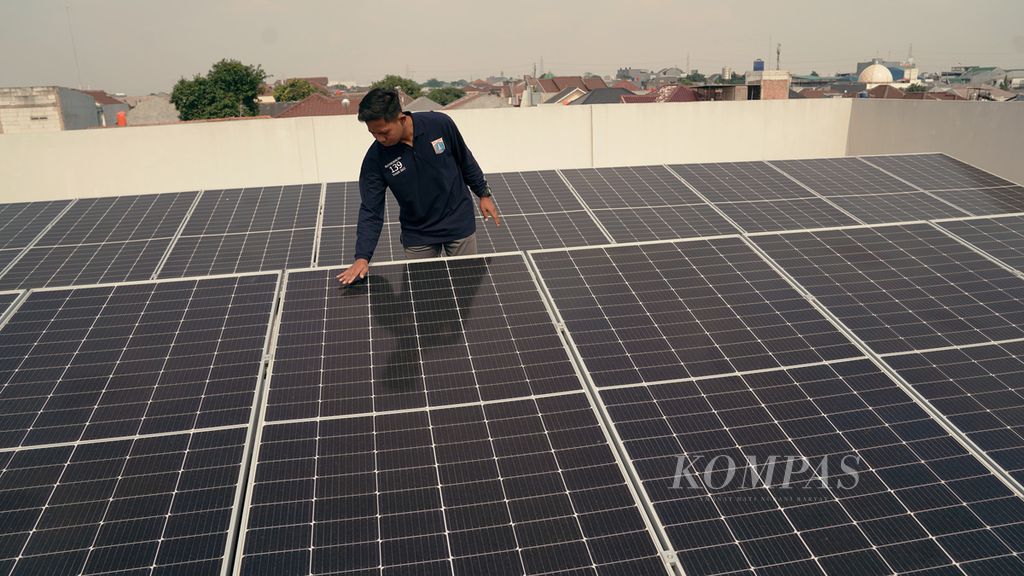 Guru mengamati panel surya yang terpasang di atap SDN Duren Sawit 14, Jakarta Timur, Kamis (29/9/2022).
