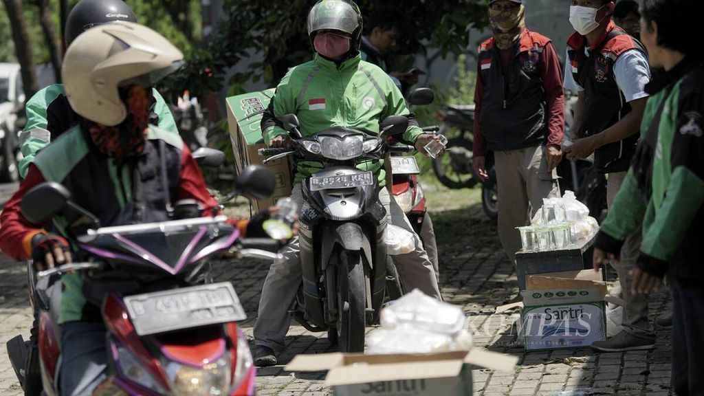 Pengemudi ojek daring antre makan siang gratis di Jalan Raya Jatiwaringin, Jakarta Timur, 2 April 2020.