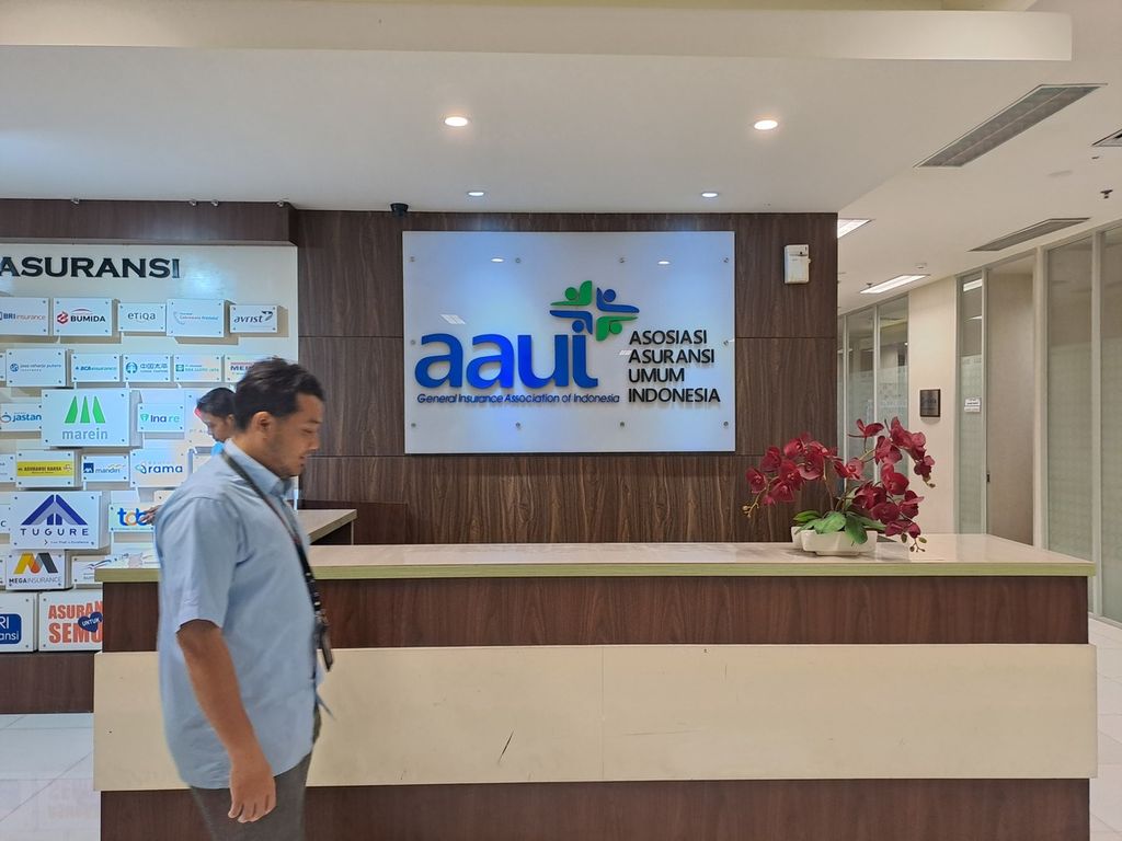 Pekerja berjalan di depan logo kantor Asosiasi Asuransi Umum Indonesia (AAUI), Jakarta, Selasa (30/5/2023).