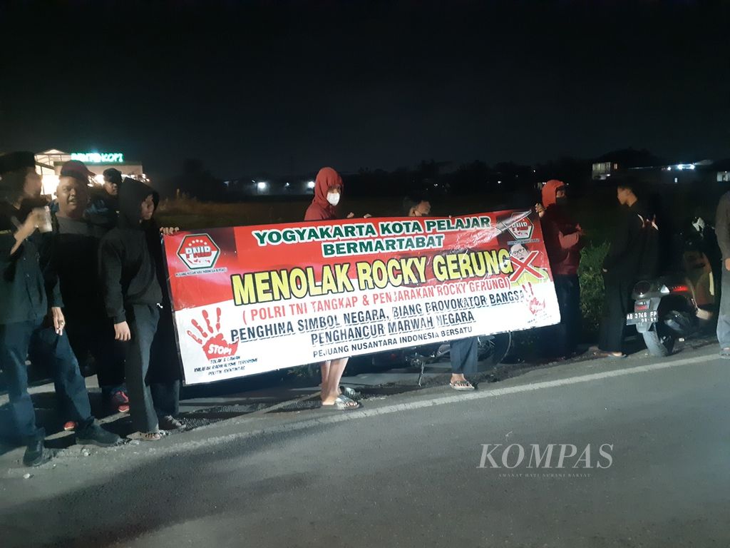 Sejumlah orang membentangkan spanduk penolakan kehadiran akademisi Rocky Gerung sebagai pembicara diskusi di kafe Bento Kopi, Kabupaten Sleman, Daerah Istimewa Yogyakarta, Rabu (2/8/2023) malam. Rocky akhirnya batal hadir dalam diskusi itu karena adanya penolakan tersebut.