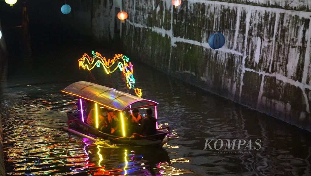 Ilustrasi ingatan masa lalu. Perahu berhiaskan lampu warna-warni melintasi Kali Pepe dalam Grebeg Sudiro, di Kota Surakarta, Jawa Tengah, Senin (16/1/2023) malam. Keberadaan wisata perahu membangkitkan ingatan tentang kejayaan jalur transportasi air di kota tersebut pada masa lampau.