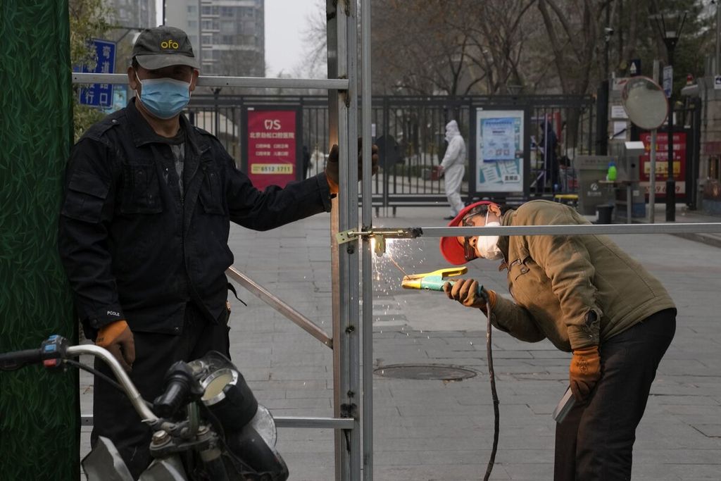 Pekerja membangun pagar pembatas untuk menutup sebuah komunitas warga di Beijing, China, Minggu (13/3/2022). Jumlah kasus baru Covid-19 meningkat tiga kali lipat pada hari Minggu di wilayah timur laut China membuat pihak berwenang memperketat akses ke Shanghai di dan mewajibkan tes Covid-19 bagi siapa saja yang ingin masuk. 