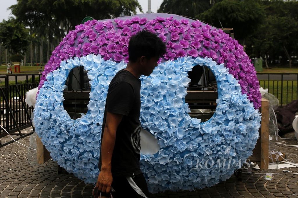 Pekerja menyelesaikan dekorasi untuk mobil hias yang akan digunakan pada acara parade Jakarnaval di malam tahun baru di Monas, Jakarta, Rabu (27/12/2023). 