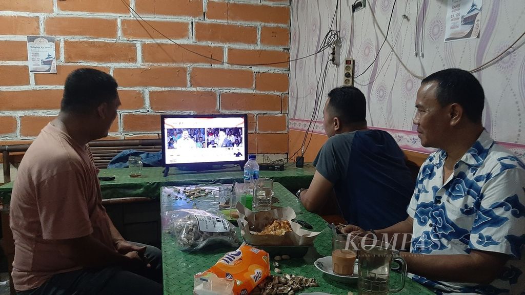 Sekelompok pemuda tengah fokus menyaksikan debat calon presiden pada televisi berukuran 24 inci di warung masakan padang di Sukabumi Selatan, Kebon Jeruk, Jakarta Barat, Selasa (12/12/2023).