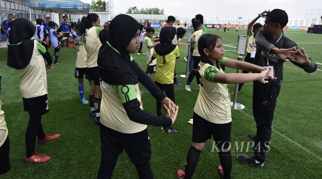 Para pemain melakukan pemanasan sebelum masuk ke lapangan dalam pertandingan hari pertama MilkLife Soccer Challenge 2023 Batch 3 yang berlangsung di Stadion Supersoccer Arena, Kudus, Jawa Tengah, Jumat (15/12/2023). 