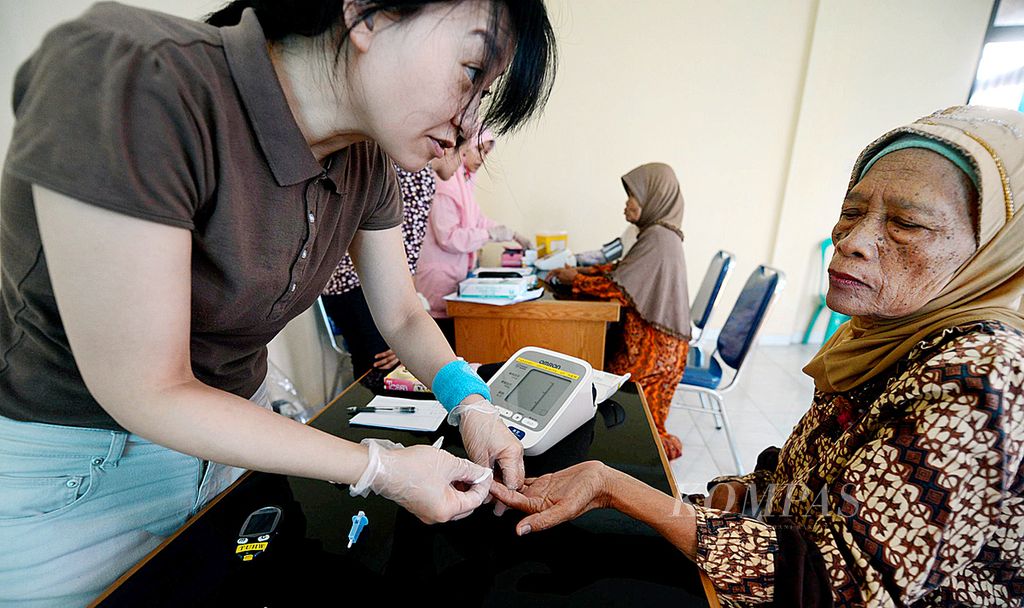 Moyo Ri (kiri), peneliti dari Departemen Keperawatan Takasaki University of Health and Welfare (Jepang), mengambil sampel darah warga di Puskesmas Kelurahan Pasir Gunung Selatan, Cimanggis, Depok, Kamis (26/12/2013).