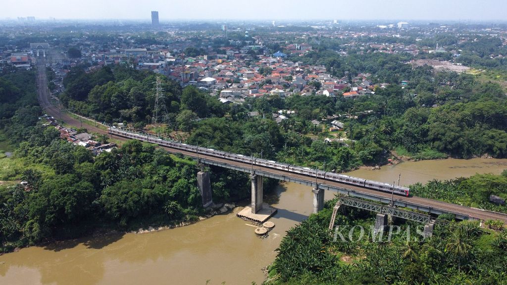 KRL Commuterline melintas di atas Sungai Cisadane di perbatasan Kecamatan Serpong, Tangerang Selatan, dengan Kecamatan Cisauk, Kabupaten Tangerang, Banten, Selasa (16/5/2023).