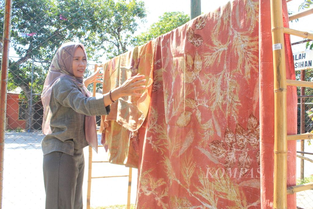Yuli Hasan menjemur kain yang menggunakan teknik <i>ecoprint</i> di Swarna Alam, Jalan Ketilang Raya, Kecamatan Harjamukti, Kota Cirebon, Jawa Barat, Selasa (1/8/2023). Dengan <i>ecoprint</i>, Yuli membuat motif menggunakan bahan alam, seperti dedaunan. 