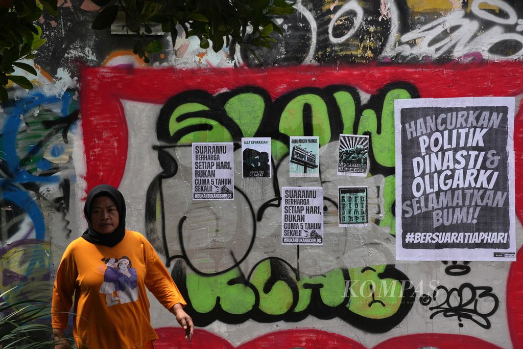 Warga melintasi poster yang mengkritisi Pemilu 2024 di Pasar Minggu, Jakarta Selatan, Selasa (13/2/2024). Sebagian publik kecewa dengan pemerintahan Joko Widodo yang dianggap mencederai demokrasi menjelang Pemilu 2024. 