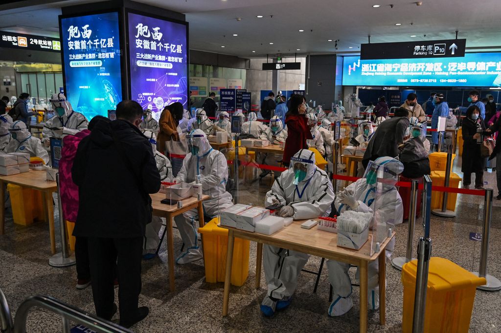 Petugas kesehatan menunggu penumpang yang hendak menjalani tes Covid-19 di Stasiun Hongqiao, Shanghai, China, Selasa (6/12/2022). 
