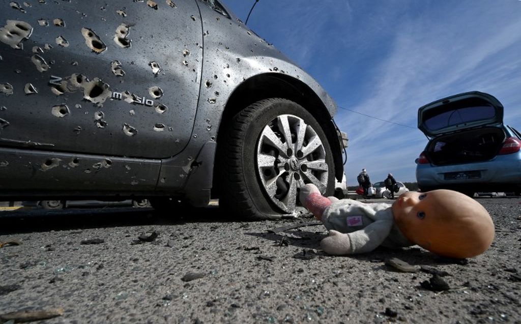 Foto yang diambil pada 12 Maret 2022 menunjukkan sebuah boneka tergeletak di samping sebuah mobil yang dipenuhi bekas terjangan peluru di Irpin, utara Kiev, Ukraina. Memasuki ke bulan ketiga, perang Rusia-Ukraina belum ada tanda-tanda surut. 