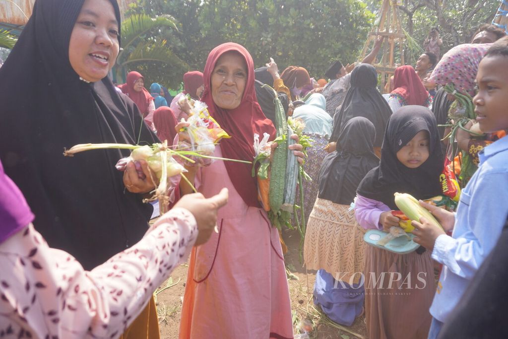 Warga berbagi sayur-mayur dan jajanan yang direbut dari gunungan dalam perayaan Tahun Baru Islam 1444 H di Sokaraja Kulon, Sokaraja, Banyumas, Jawa Tengah, Sabtu (30/7/2022).