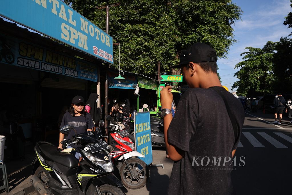 Penjual jasa persewaan sepeda motor memotret penyewa sepeda motor di depan Stasiun Lempuyangan, Yogyakarta, 13 Mei 2022. 