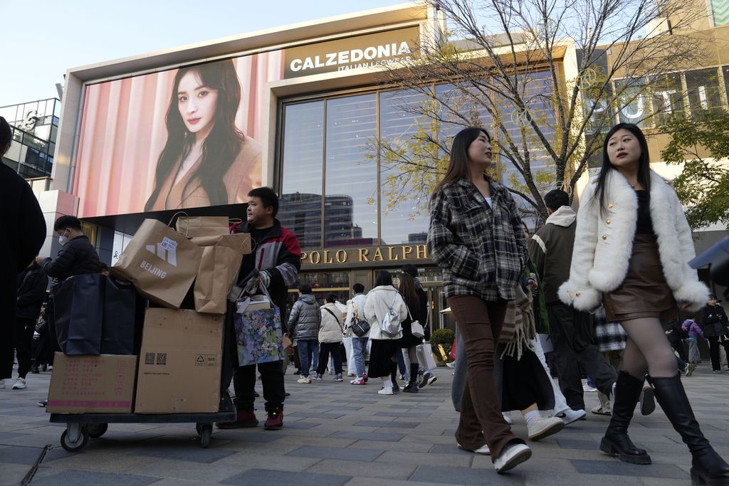 Seorang pengantar barang mengumpulkan paket ketika pembeli mengunjungi distrik mal populer di Beijing, China, pada 18 November 2023.