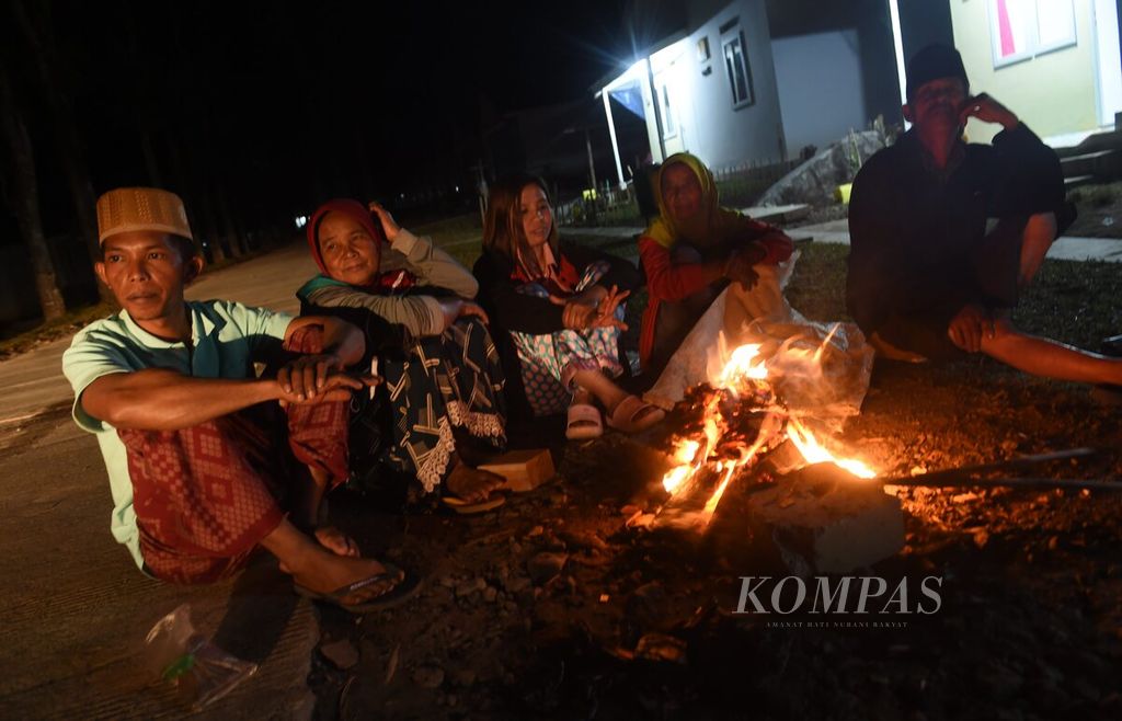 Warga hunian tetap Sumbermujur di Kecamatan Candipuro, Kabupaten Lumajang, Jawa Timur, duduk di sekitar api unggun untuk mengusir dingin, Sabtu (9/7/2022) malam. Kawasan hunian tetap tersebut merupakan bagian dari upaya penanganan pascabencana erupsi Gunung Semeru. 