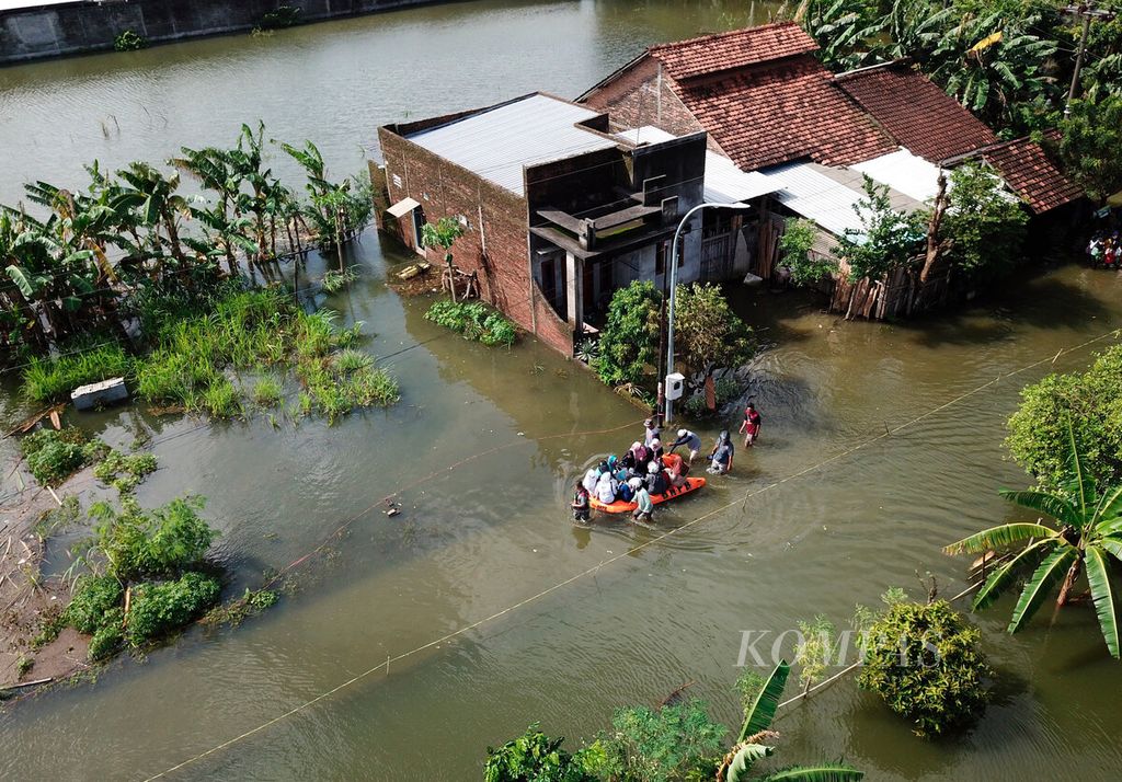 Warga menggunakan perahu untuk menuju rumah mereka yang masih terendam banjir di Desa Kedungdowo, Kecamatan Kaliwungu, Kabupaten Kudus, Jawa Tengah, Rabu (4/1/2023). 