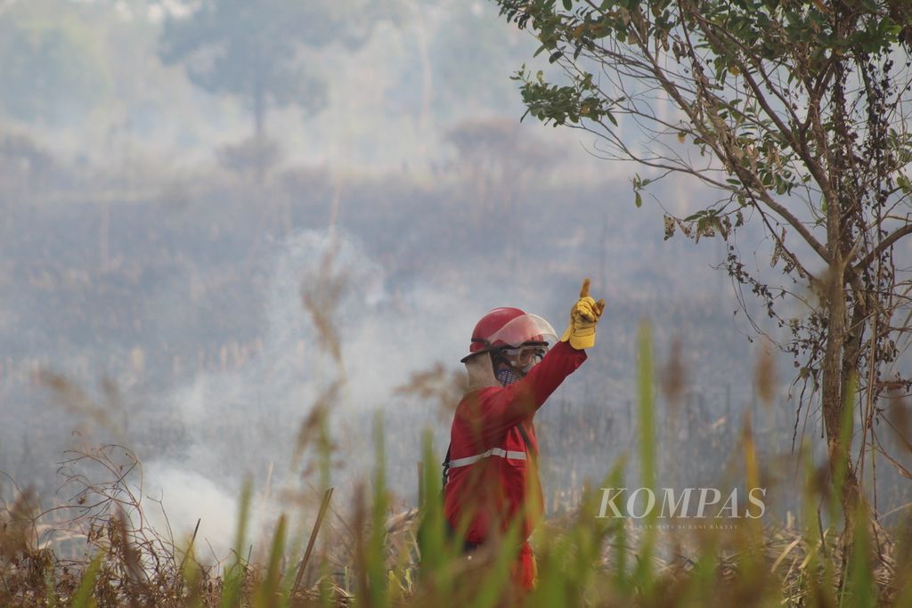 Seorang petugas Manggala Agni sedang memberikan isyarat kepada rekannya mengenai titik api baru di Kawasan Ibul Besar I, Kecamatan Pemulutan, Kabupaten Ogan Ilir, Sumatera Selatan, Rabu (30/8/2023). 