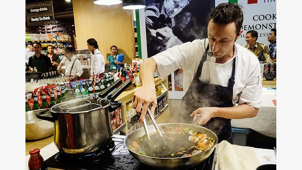 Chef Alessandro De Boni mempraktikkan cara memasak salah satu menu khas Italia, black ink tagliolini with seafood sauce, di ajang The Extraordinary Italian Taste, Jumat (17/11), di Ranch Market, Grand Indonesia, Jakarta.