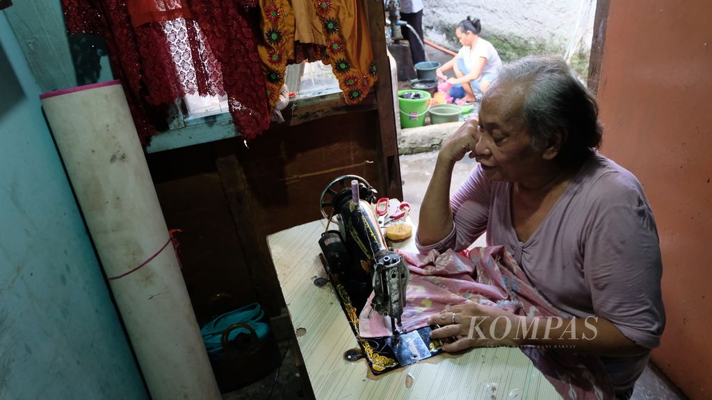 Dora (64), transpuan asal Jawa Timur, sedang menjahit di rumahnya di kawasan padat penduduk di Jatinegara, Jakarta Timur, pada Selasa (19/7/2022). Ia merantau ke Jakarta sejak 30 tahun lalu, kemudian bertahan hidup dengan mengamen, bekerja serabutan, hingga menjahit.