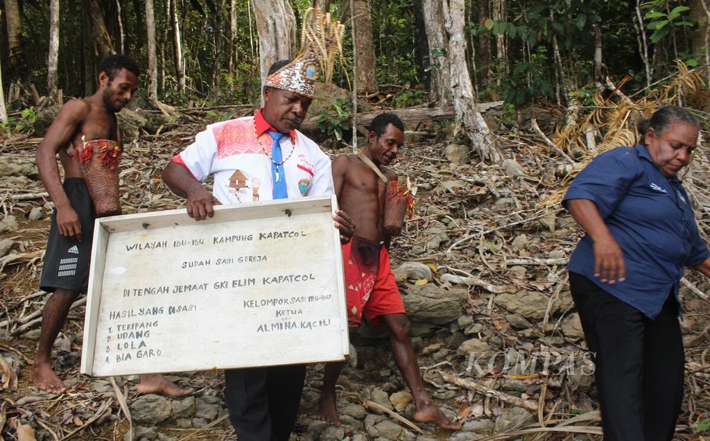 Yesaya Kacili (53), pendeta di Gereja Kristen Injili (GKI) Elim Kapatcol, membawa papan sasi di Misool Barat, Kabupaten Raja Ampat, Papua Barat Daya, Senin (25/3/2024).