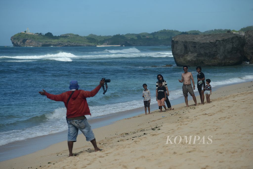 Wisatawan menggunakan jasa warga lokal yang berprofesi sebagai juru foto di Pantai Indrayanti, Kecamatan Tepus, Gunungkidul, DI Yogyakarta, Kamis (25/1/2024).