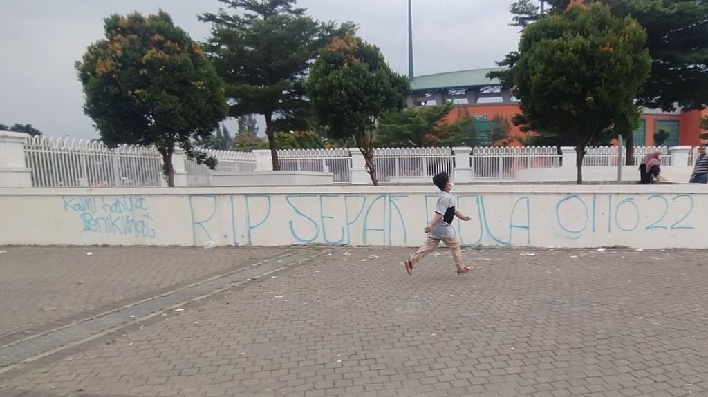 Seorang anak kecil berjalan di luar Stadion Pakansari, Kabupaten Bogor, Jawa Barat, Minggu (9/10/2022). Di tembok belakang anak kecil itu tertulis, Kami hanya penikmat, RIP Sepak Bola 01102022.