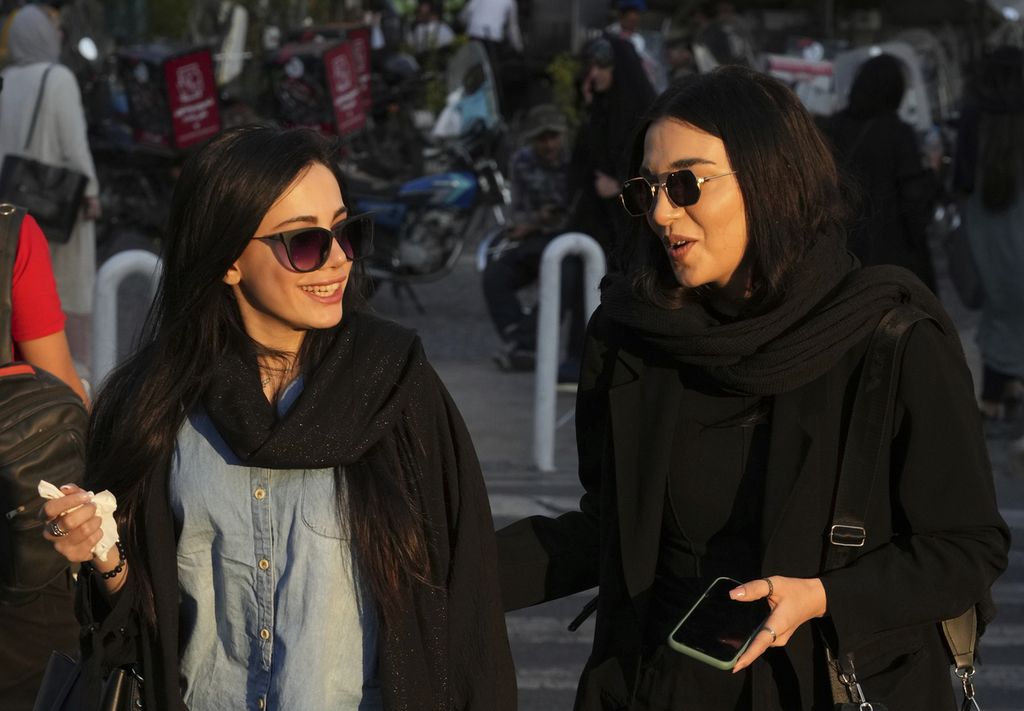 Dua perempuan tanpa berkerudung berjalan sambil berbincang-bincang di sekitar kawasan bisnis, Tajrish, wilayah utara Teheran, Iran, 29 April 2023. 