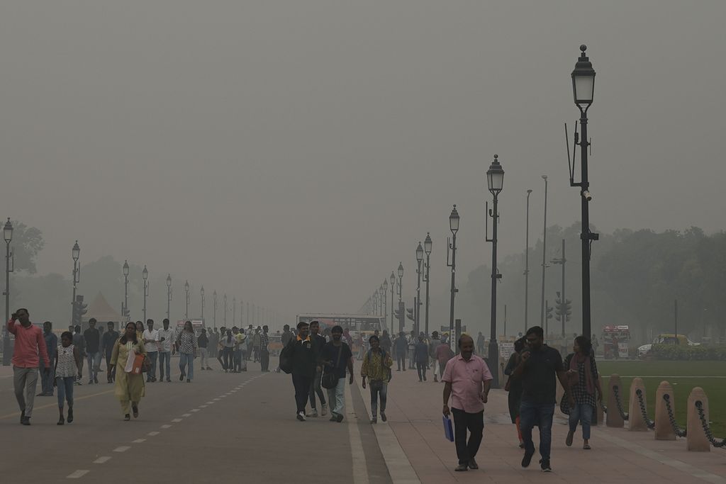 Warga berjalan di tengah kabut dan asap di Kartavya Path, New Delhi, India, 3 November 2023. Otoritas menutup sekolah dan melarang kegiatan konstruksi untuk mengendalikan polusi terparah pada musim kabut asap ini. 