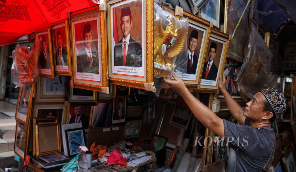Fathur (50) menata sejumlah dagangan foto Prabowo Subianto dan Gibran Rakabuming Raka sebagai Presiden dan Wakil Presiden 2024-2029 di lapaknya di kawasan Pasar Baru, Jakarta, Minggu (31/3/2024). 
