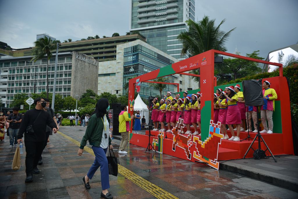 Warga melintas di depan pertunjukan Christmas Carol yang digelar di depan Plaza Indonesia, Jakarta Pusat, Kamis (22/12/2022). 