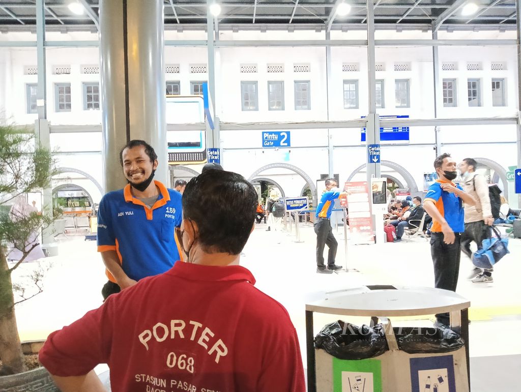 Interaksi di antara <i>porter</i> sembari menunggu pergantian jam kerja di Stasiun Pasar Senen, Kamis (9/3/2023). Untuk jam kerja siang atau tim ganjil menggunakan seragam merah, sementara tim genap atau jam kerja malam menggunakan seragam merah
