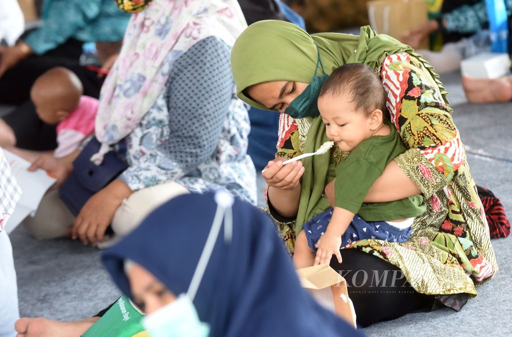 Ibu memberi makan bayinya dengan bubur sehat saat peluncuran Gebyar Lomba Balita Sehat di halaman Balai Kota Surabaya, Jawa Timur, Rabu (26/1/2022). 