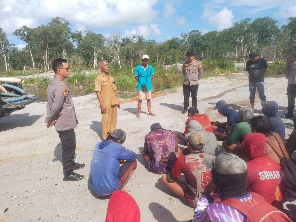 Tim gabungan Polres Belitung Timur dan Polsek Manggar membawa pejuang lingkungan Yudi Amsoni (berdiri baju toska) berhadapan dengan petambang timah ilegal di Desa Sukamandi, Kecamatan Damar, Kabupaten Belitung Timur, Provinsi Kepulauan Bangka Belitung, Senin (13/5/2024). Hal itu merupakan dampak dari suara lantang Yudi yang tersiar dalam program 60’ Special Report berjudul ”Jejak Tamak Korupsi Tambang Timah Rp 271 T” yang disiarkan Kompas TV, Minggu (12/5/2024). 