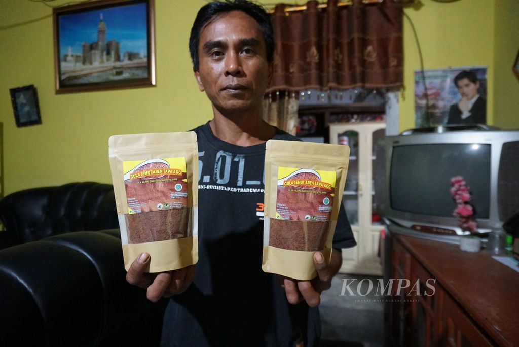 Adang Akab (45) memamerkan kemasan Gula Semut Aren Tapa Aog buatan kelompoknya, Kelompok Tani Hutan Harapan Baru, Selasa (19/7/2022), di rumahnya yang terletak di Desa Tapa Aog, Lolayan, Bolaang Mongondow, Sulawesi Utara.