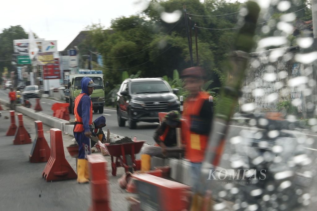 Pekerja memasang pembatas jalan di tengah Jalan Wates Kilometer 9, Bantul, Daerah Istimewa Yogyakarta, Selasa (2/4/2024). Berbagai infrastruktur pendukung kelancaran perjalanan mudik 2024 mulai disiapkan.