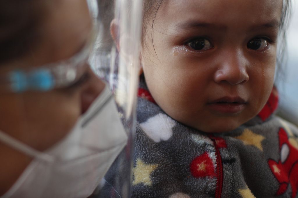 Seorang anak menangis saat ibunya mempersiapkan dirinya untuk disuntik vaksin flu di Mexico City, Kamis (1/10/2020).