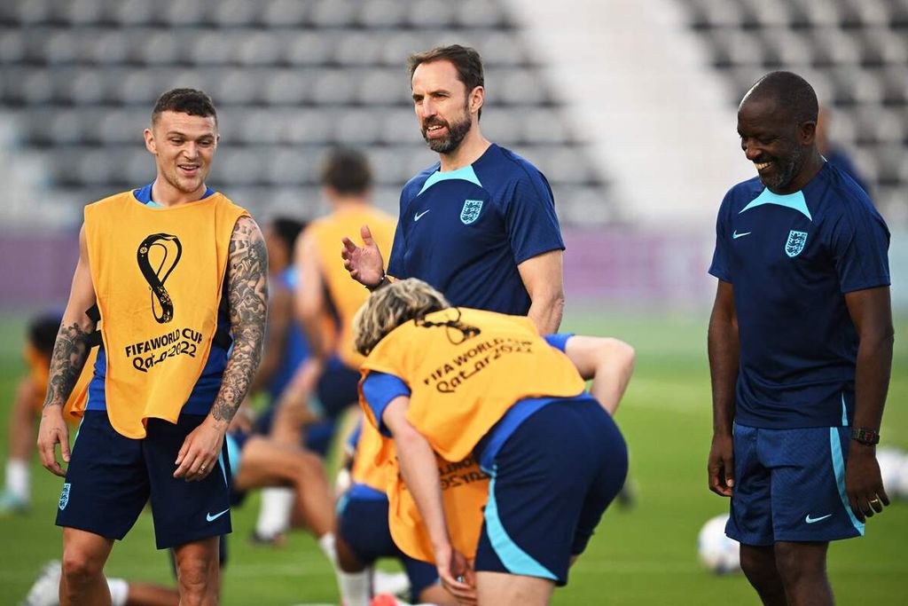Pelatih Inggris Gareth Southgate (tengah) bergurau dengan asisten pelatih Chris Powell (kanan) dan bek Kieran Trippier (kiri) pada sesi latihan tim di Stadion Al Wakrah, selatan Doha, Qatar, Minggu (20/11/2022). 