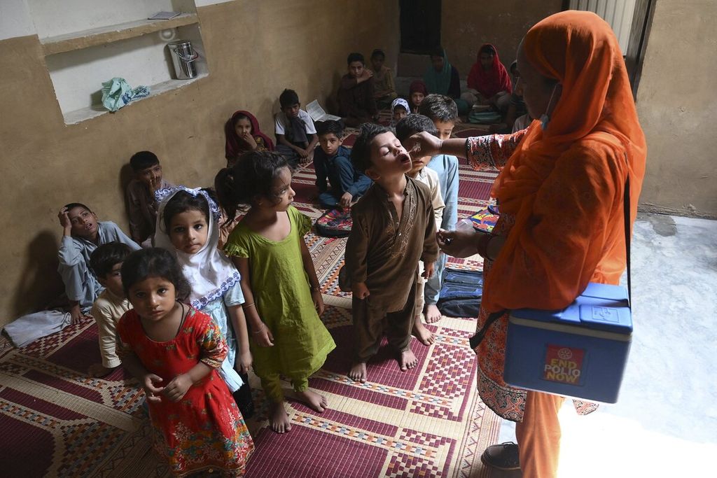 Anak-anak berbaris untuk menerima vaksin polio di Lahore, Pakistan. 