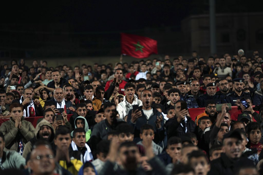 Warga Palestina di kamp pengungsi di Rafah, selatan Gaza, berkumpul sambil mengibarkan bendera Maroko saat menyaksikan bersama laga Maroko versus Perancis pada Piala Dunia Qatar, Rabu (14/12/2022) malam.