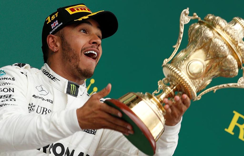 Pebalap tim    Mercedes  asal Inggris,  Lewis Hamilton, mengangkat tropi dan merayakan keberhasilannya memenangi balapan F1 seri Inggris di Sirkuit Silverstone, Inggris, Minggu (16/7) malam WIB. 