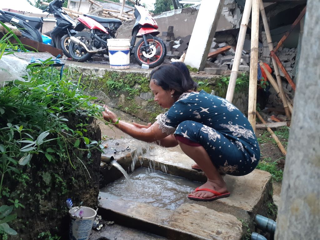 Nurjanah, pengungsi di Desa Gasol, Kecamatan Cugenang, mengunakan aliran irigasi sawah untuk membersihkan badan, Rabu (23/11/2022). Selain menghancurkan rumah, gempa bermagnitudo 5,6 mengakibatkan putusnya aliran air bersih serta tandon penyimpan air turut rusak.