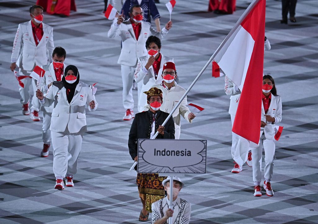 Pengibar bendera Indonesia, Nurul Akmal, dan rombongan delegasi Indonesia berparade saat upacara pembukaan Olimpiade Tokyo 2020 di Stadion Olimpiade Tokyo, 