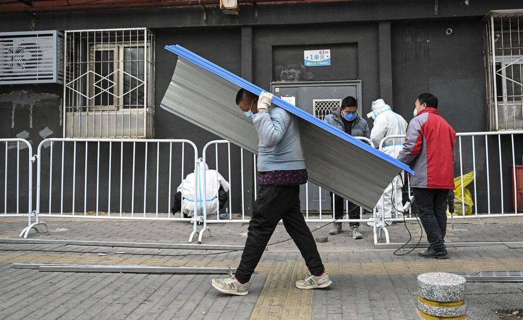 Seorang pria membawa sepotong pagar melewati kawasan permukiman yang dikarantina total akibat kebijakan ketat terkait Covid-19 di Beijing, China, 24 November 2022. 