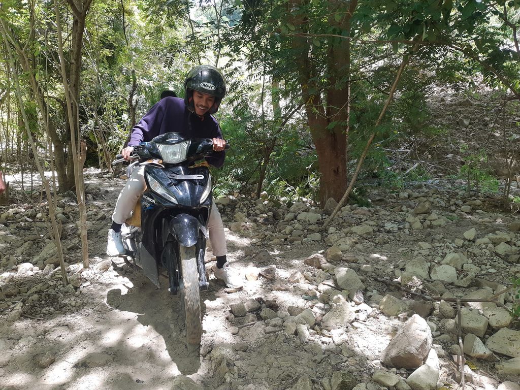 Pengguna sepeda motor memaksa melewati jalan setapak lantaran terjadi longsor di ruas Jalan Timor Raya, tepatnya di Kelurahan Takari, Kabupaten Kupang, Nusa Tenggara Timur, pada Minggu (19/2/2022). 